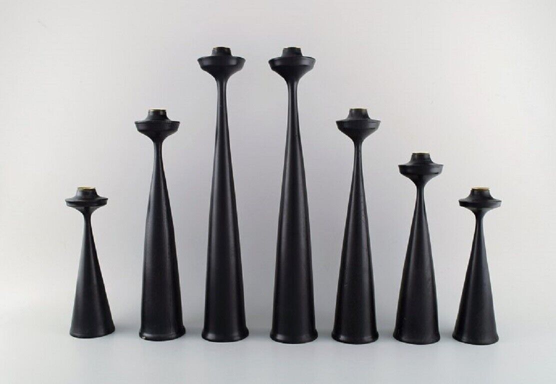 A collection of seven Scandinavian designer candlesticks in wood and brass