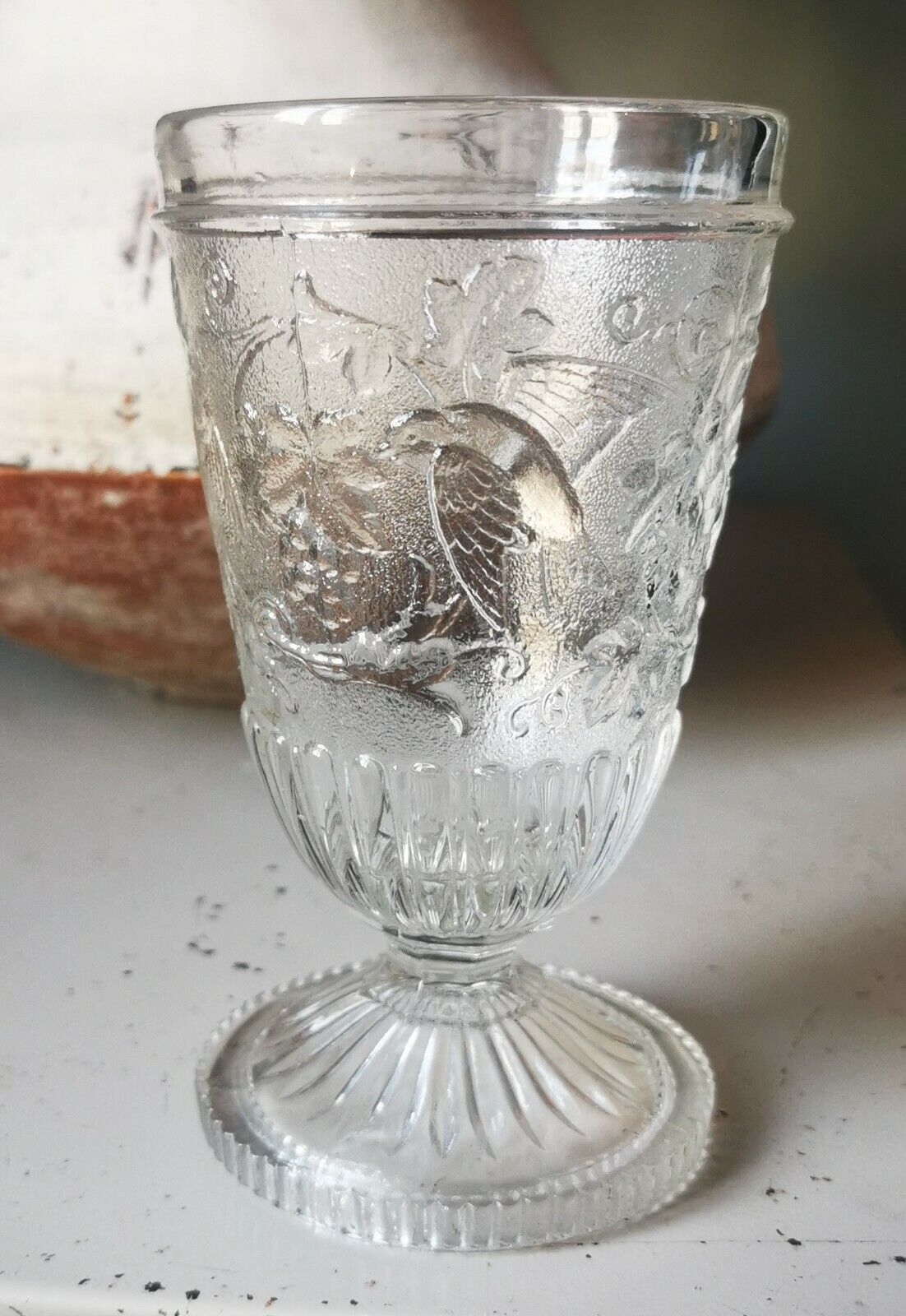 Antique pressed drinking glass with grape and bird decorations from c 1900