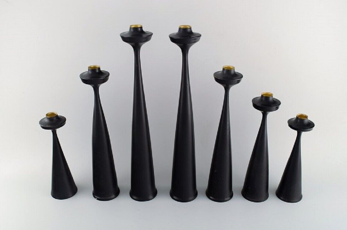 A collection of seven Scandinavian designer candlesticks in wood and brass