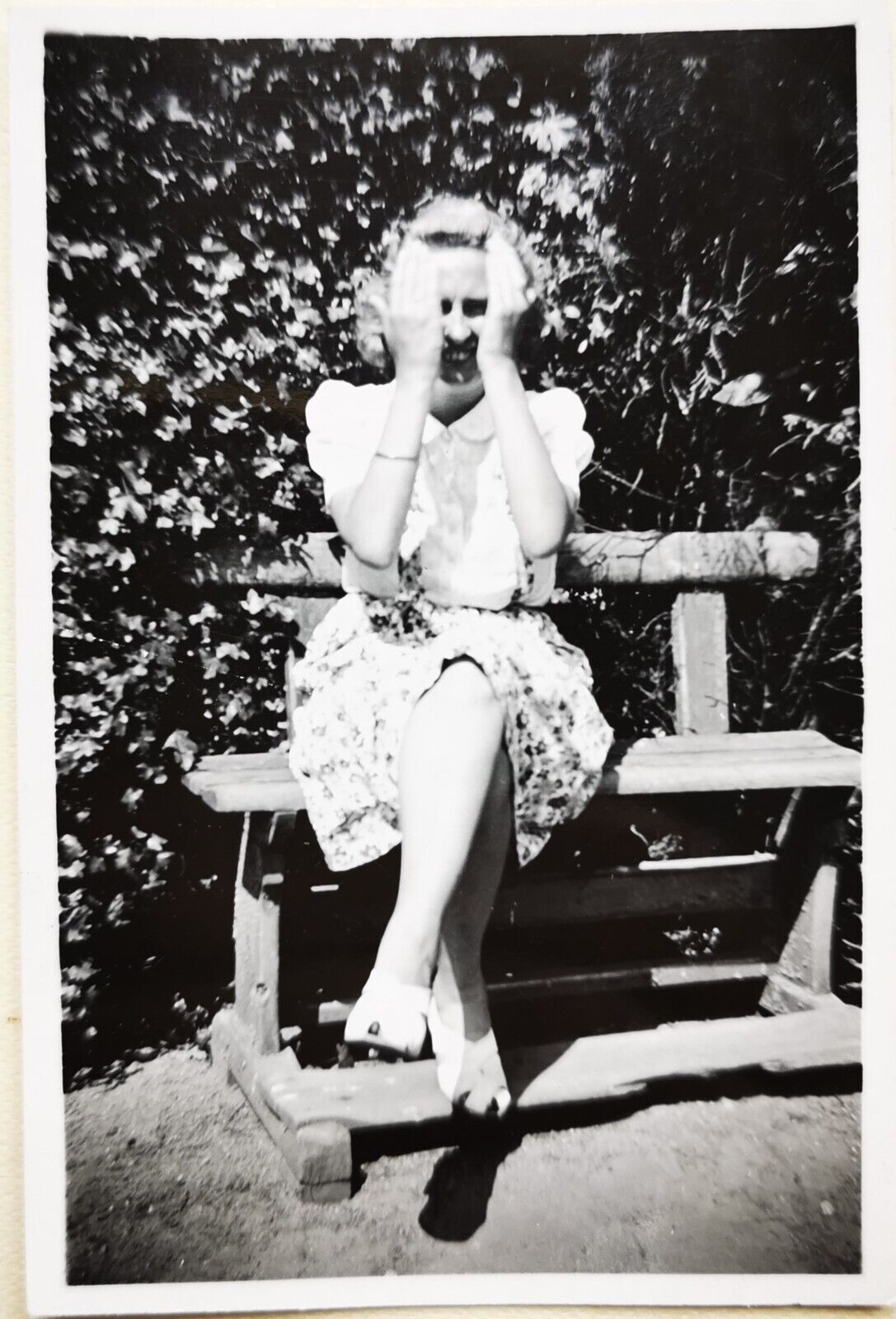 Old photo: Young blonde woman hiding her face sitting on small bench  Fo3026