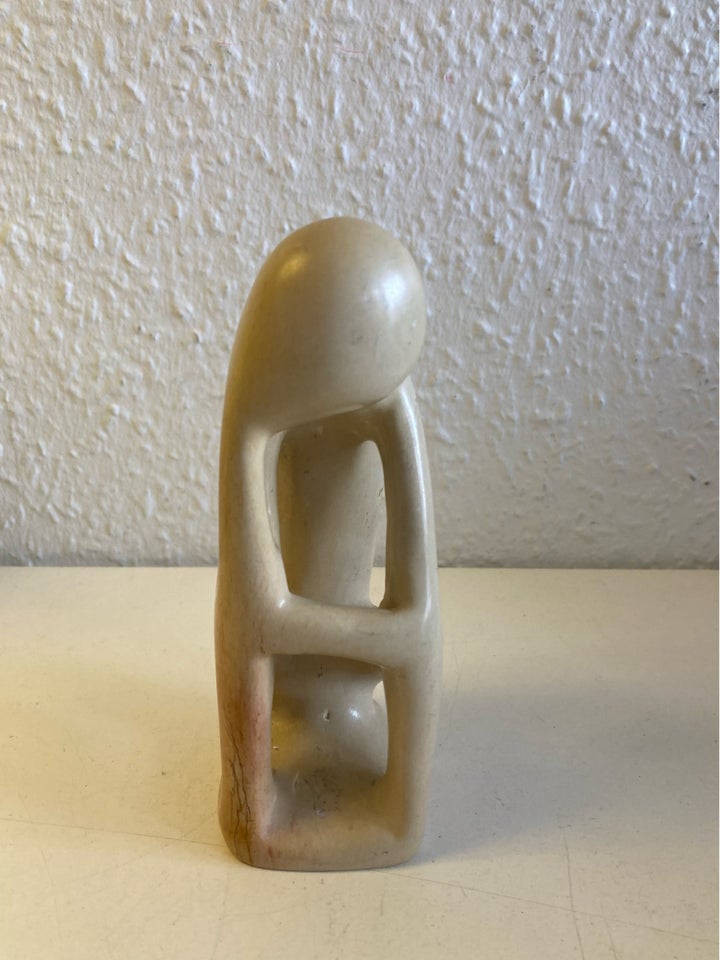 Beige sten skulptur menneske tager