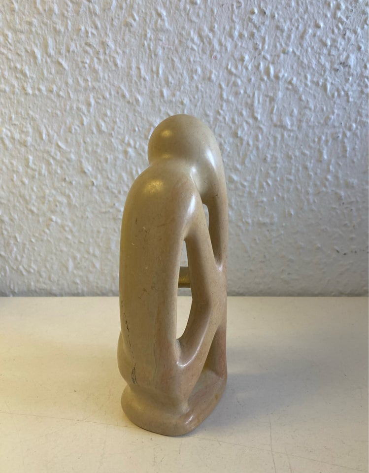 Beige sten skulptur menneske tager