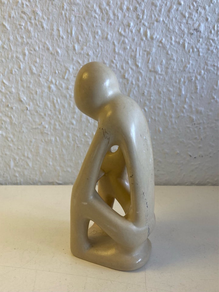 Beige sten skulptur menneske tager