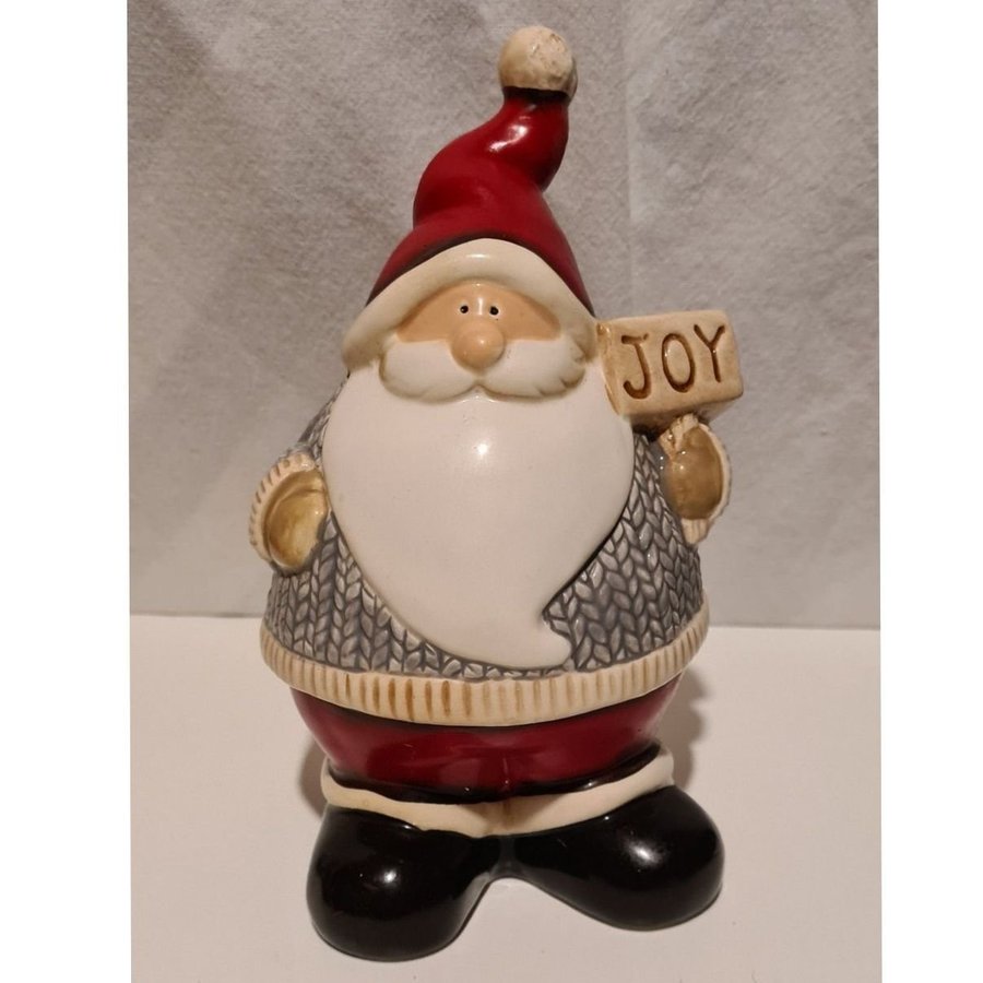 Tomte i porslin med skylt texten JOY. Tomten är ca 17 cm hög.p