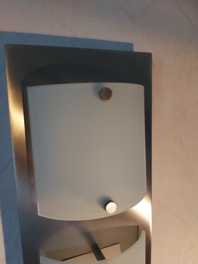 Vägglampa i vitmetall med tre ljuskällor. Inbyggd dimmer.