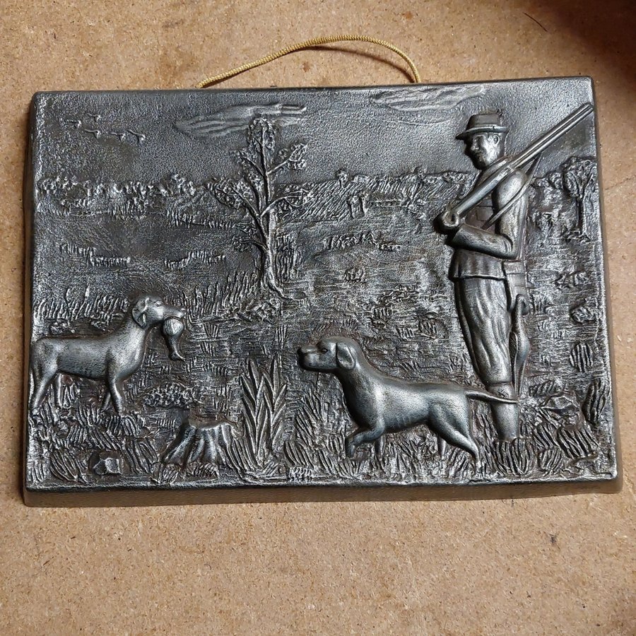 Metallrelief med jägare och hundar