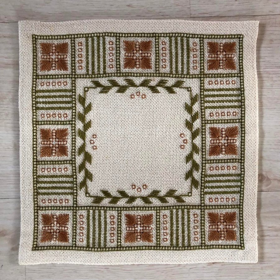 Handbroderad liten duk i milda färger för vintagekänsla.