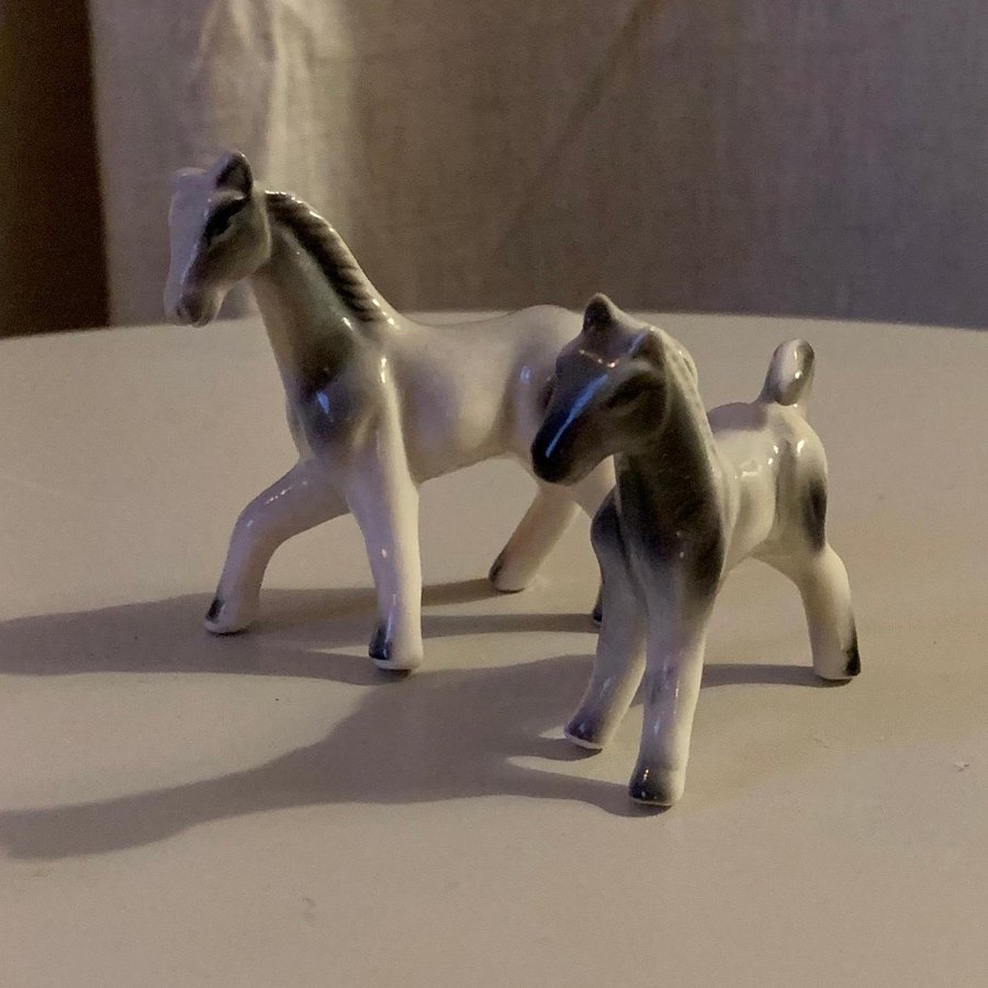 Två miniatyrhästar i porslin grå/vita