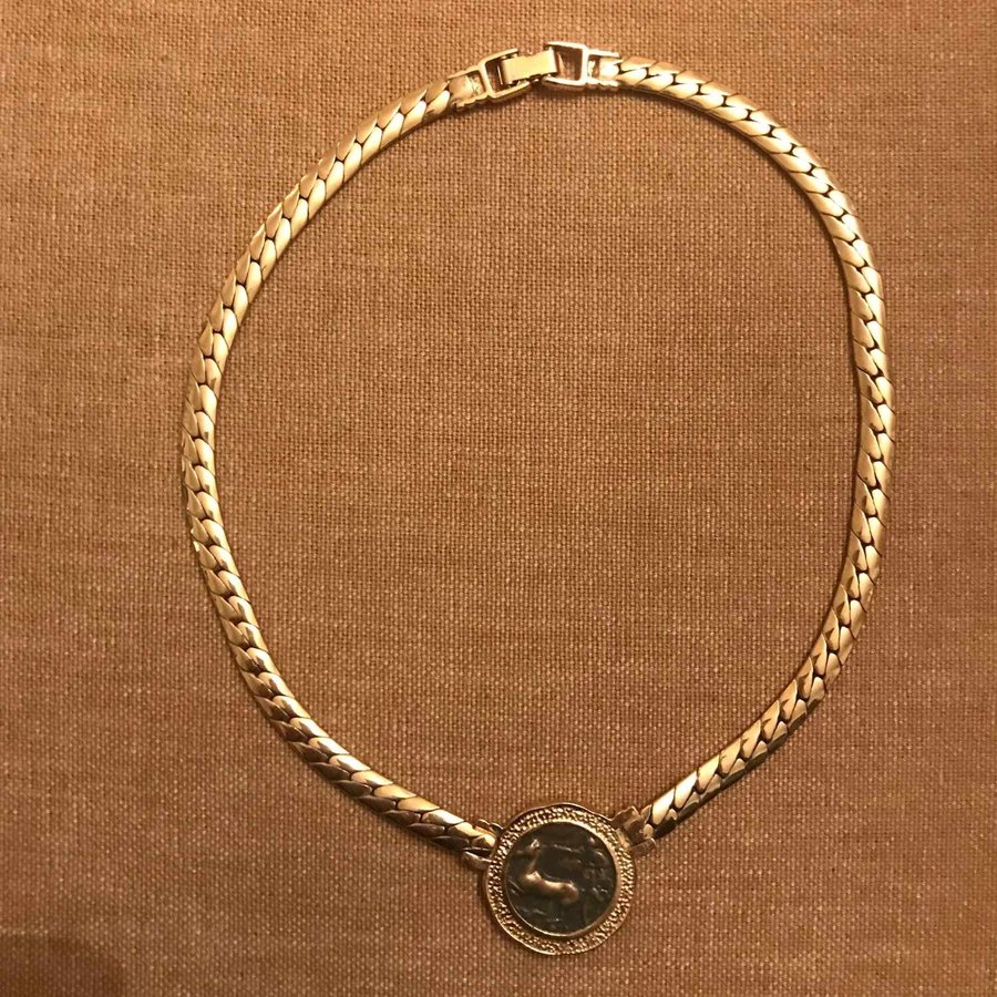 Halsband i guldfärgad metall myntliknade fast berlock