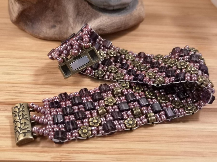 Ett Peyote armband i aubergine färgade pärlor och brons dekor
