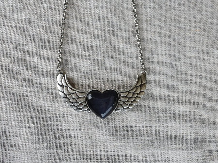 Halsband med vingar och ett svart hjärta i mitten nickelfritt