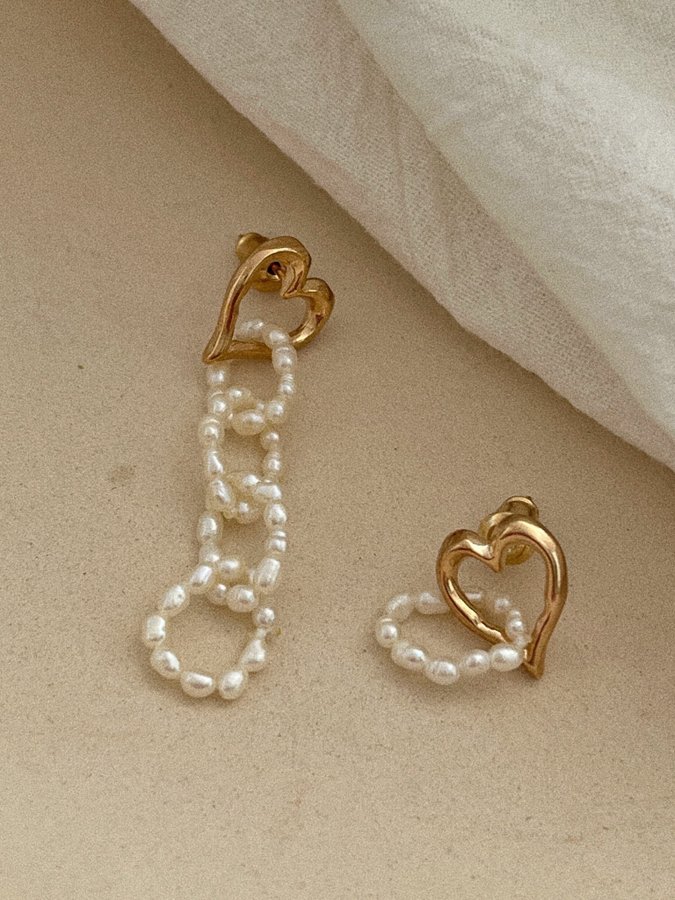Guldfärgade örhängen med pärlor med asymmetrisk design