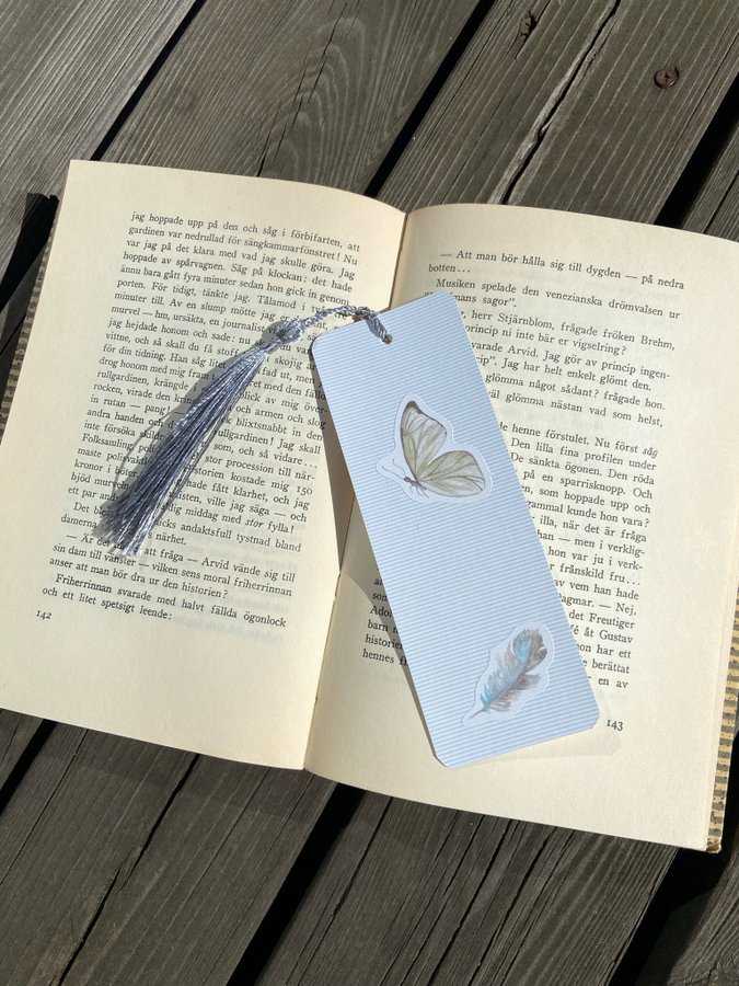 Handgjort bokmärke fjäril och fjäder blå