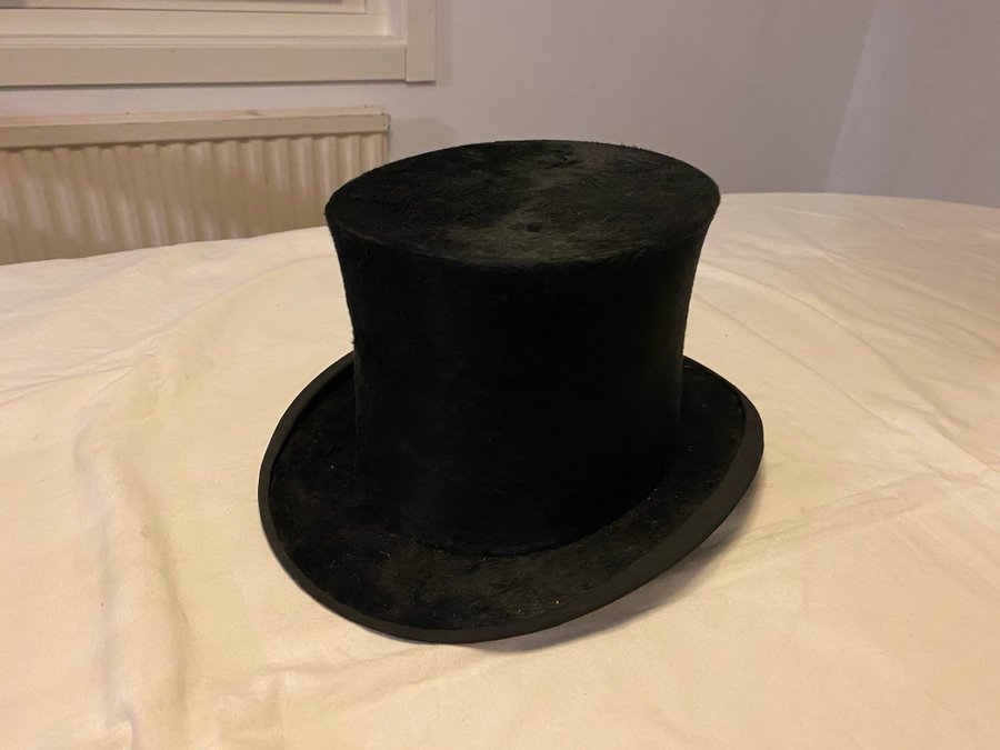 Gammal hög hatt märkt med relieftryck på insidan BEST LONDON i sliten hattask