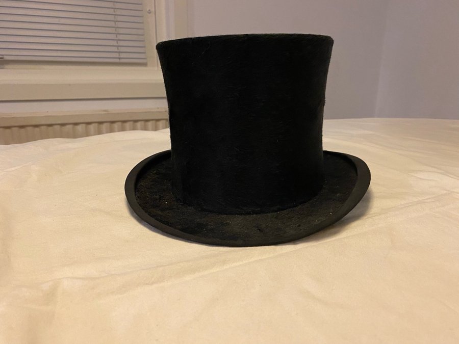 Gammal hög hatt märkt med relieftryck på insidan BEST LONDON i sliten hattask