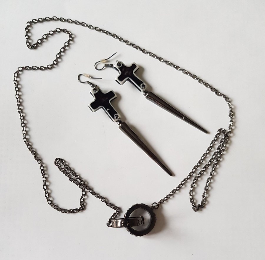 Långt halsband med två ringar och örhängen med dödskallar i ett kors och strutar