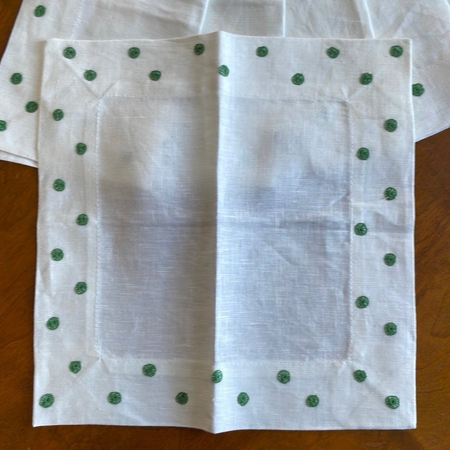 Sex servetter i vitt linne med broderade prickar samt fyra behållare i linne