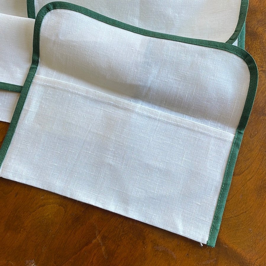 Sex servetter i vitt linne med broderade prickar samt fyra behållare i linne