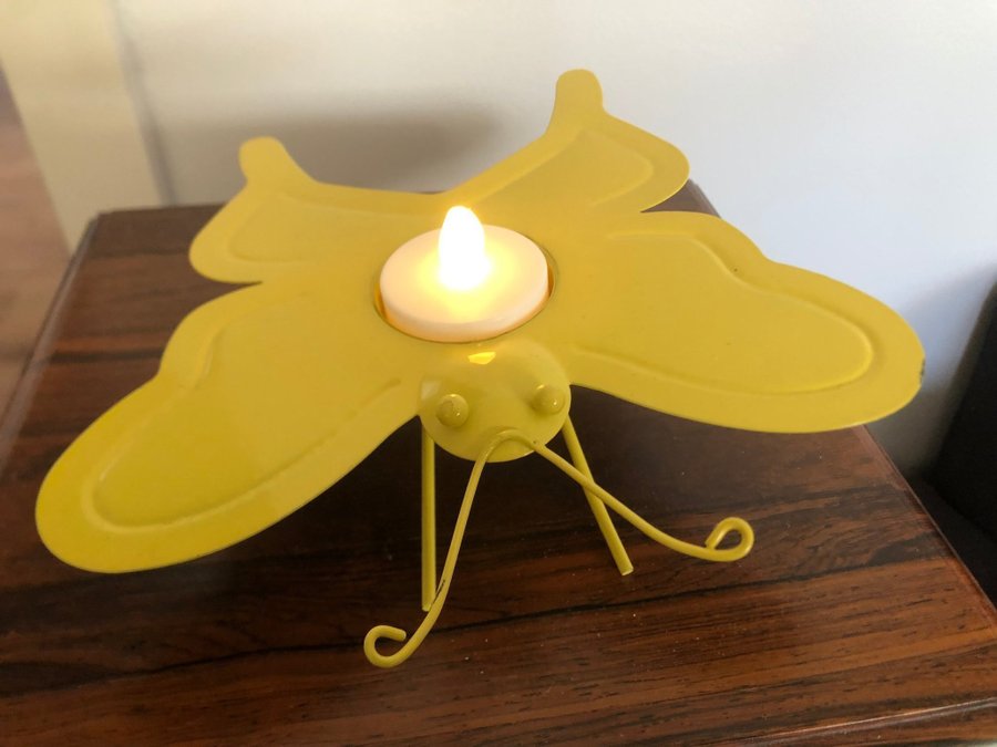 En ljushållare i form av fjäril i gul färg
