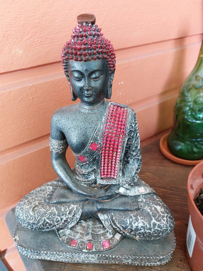 Buddhastaty i silver och röda stenar