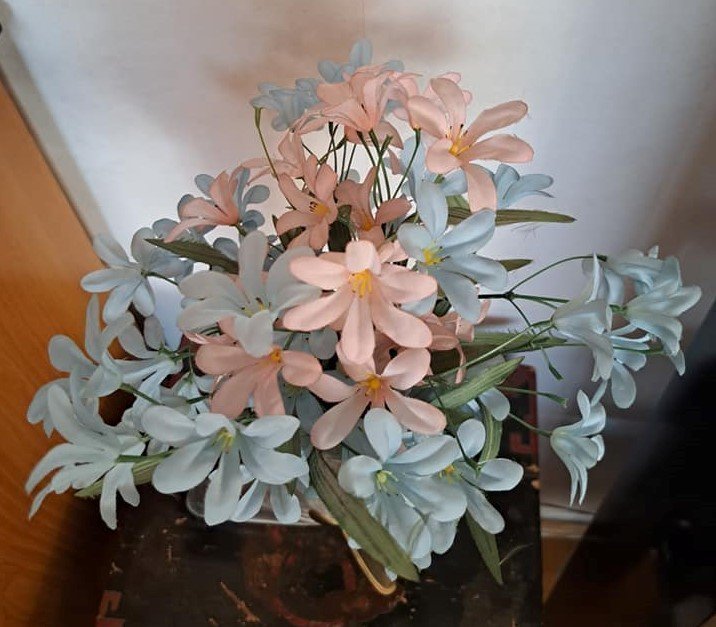 En bukett konstgjorda blommor i ljusblått och ljust rosa