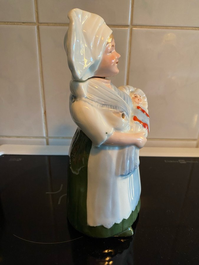 Fin gammal likör flaska i keramik med huvud som korksjuksköterska med spädbarn