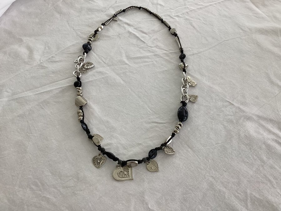 Halsband i textilband med silverfärgade berlocker och andra detaljer