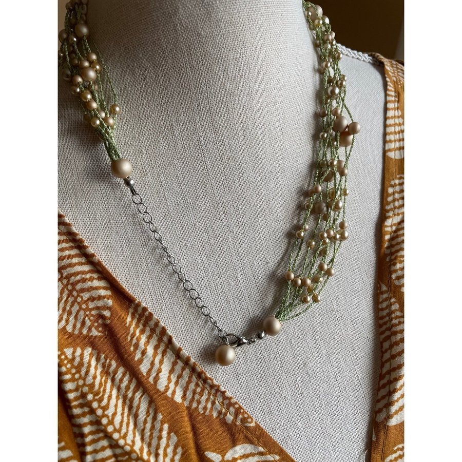 Halsband med flera rader av ljusgrön tråd och kulor i guld och ljus brons