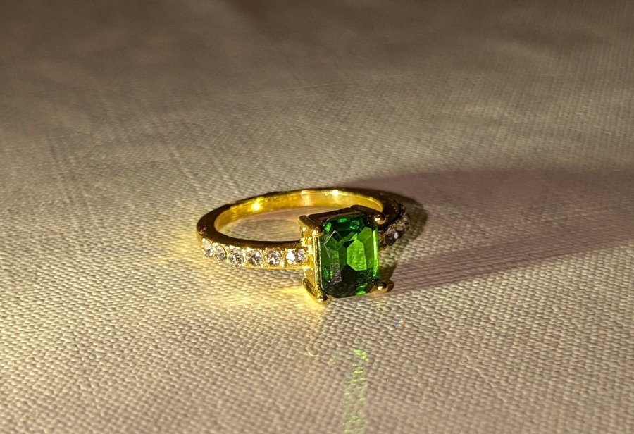 Guldfärgad ring med grön sten och strasstenar