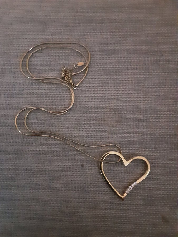 Långt halsband med ett hjärta hängande