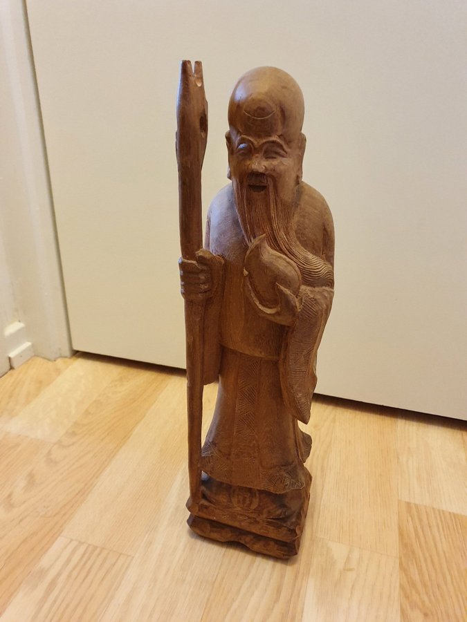 Träskulptur av en asiatisk man med stav