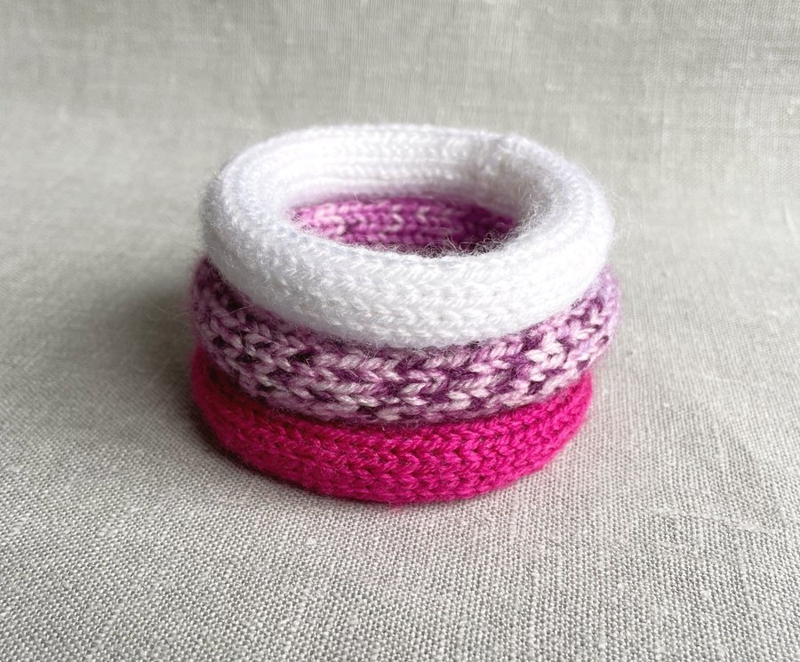 Tre stycken stickade armband i rosa vitt och lila