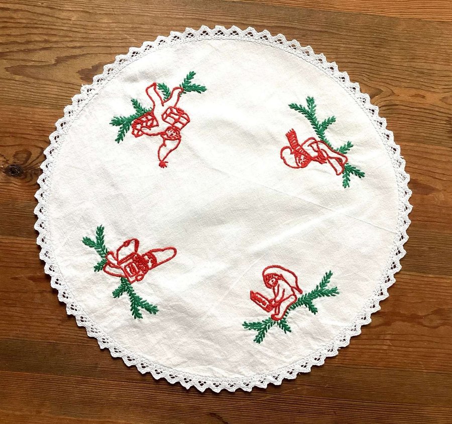 Söt rund julduk med broderade tomtar i rött och grönt Med spetskant runt om Duk