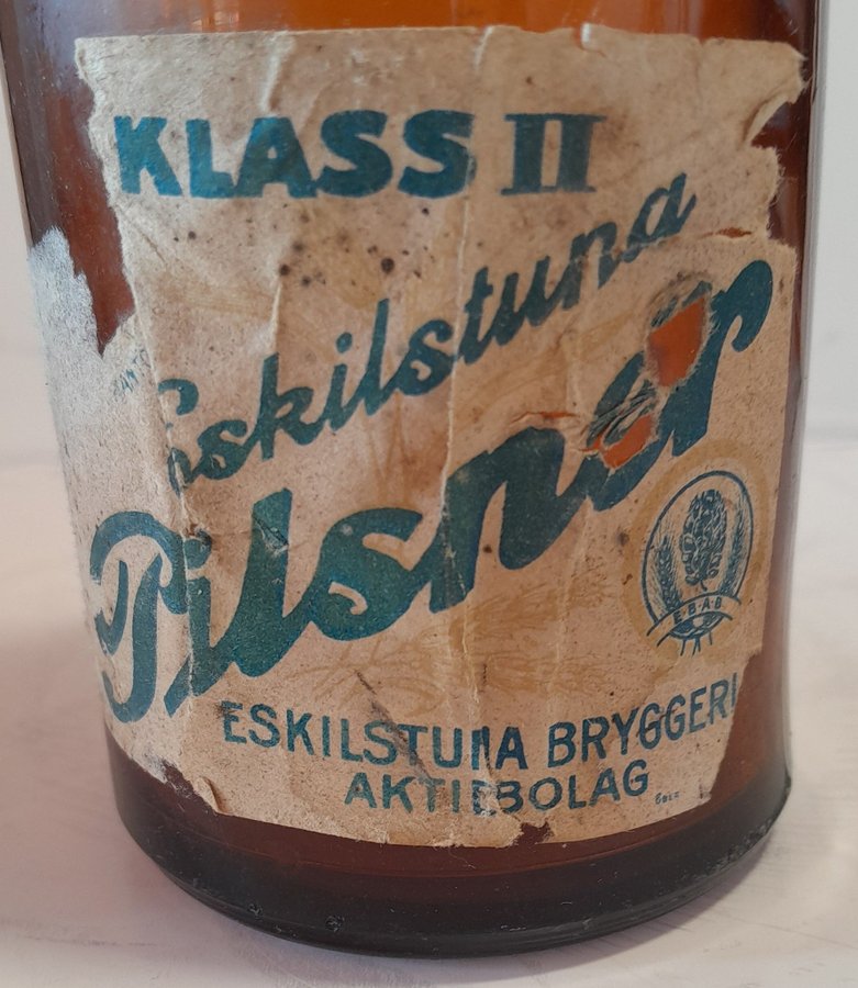 Pilsnerflaska med delar av etikett, Klass II Eskilstuna pilsner