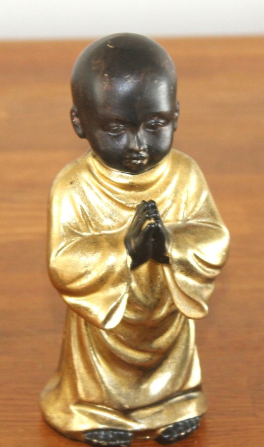 Buddha figur bedjande pojke i svart och guld