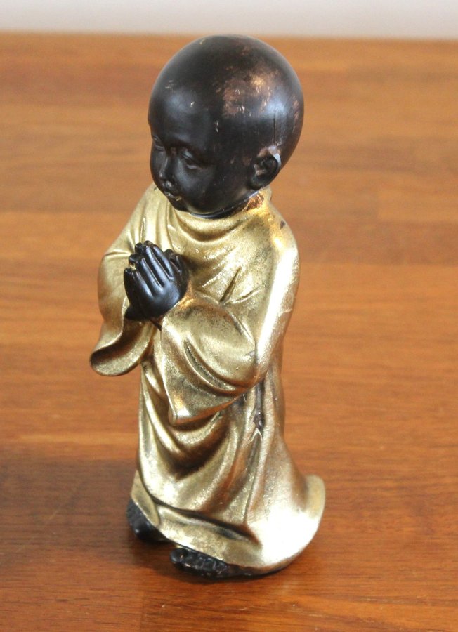 Buddha figur bedjande pojke i svart och guld