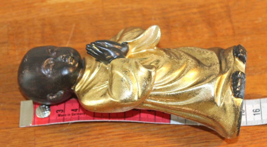 Buddha figur bedjande pojke i svart och guld