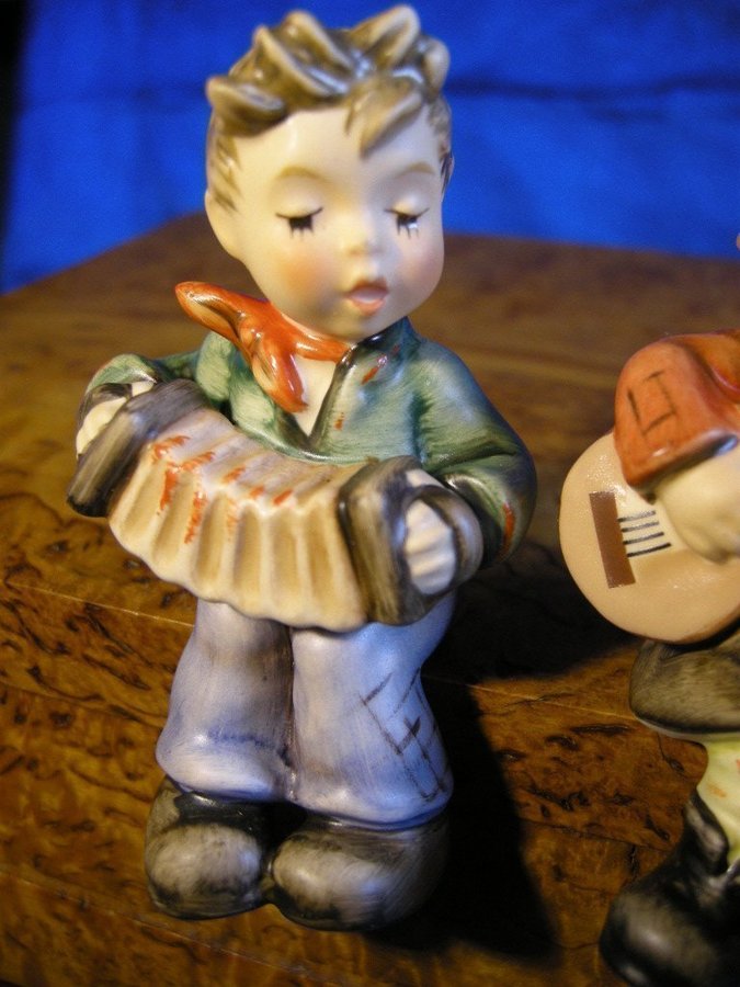 Sittande pojke och flicka spelande dragspel och gitarr. Fina Hummel figuriner