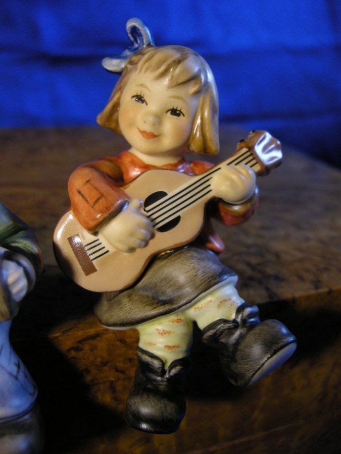 Sittande pojke och flicka spelande dragspel och gitarr. Fina Hummel figuriner