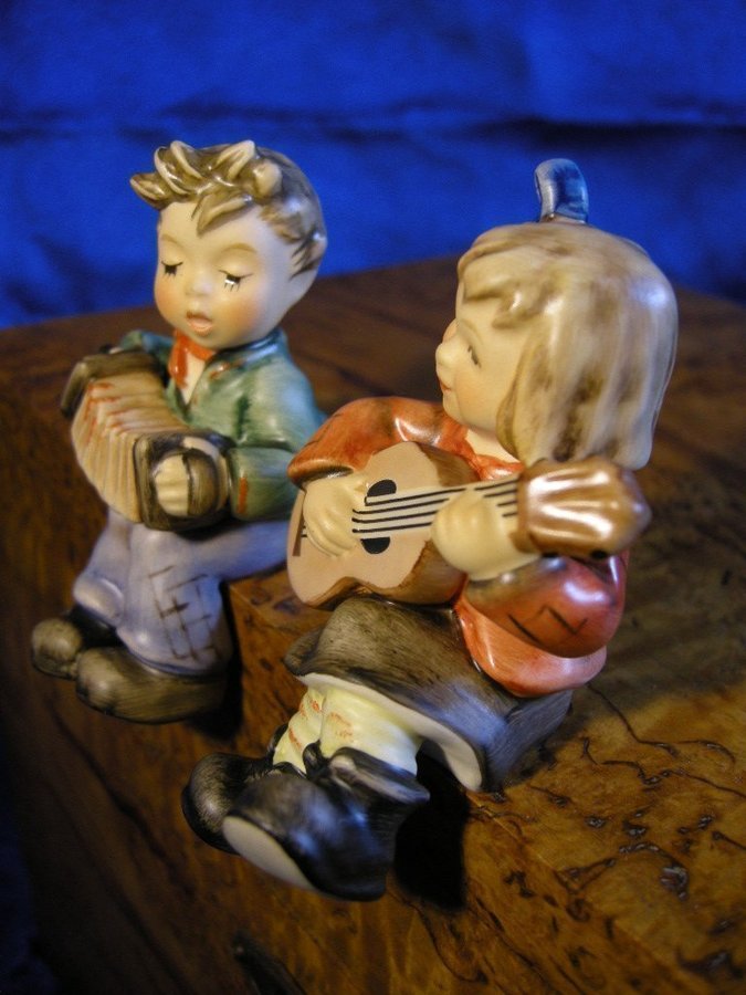 Sittande pojke och flicka spelande dragspel och gitarr. Fina Hummel figuriner