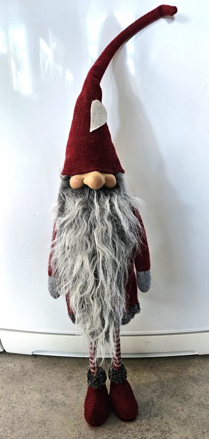 Stor söt tomte med långa smala ben och längt grått skägg.