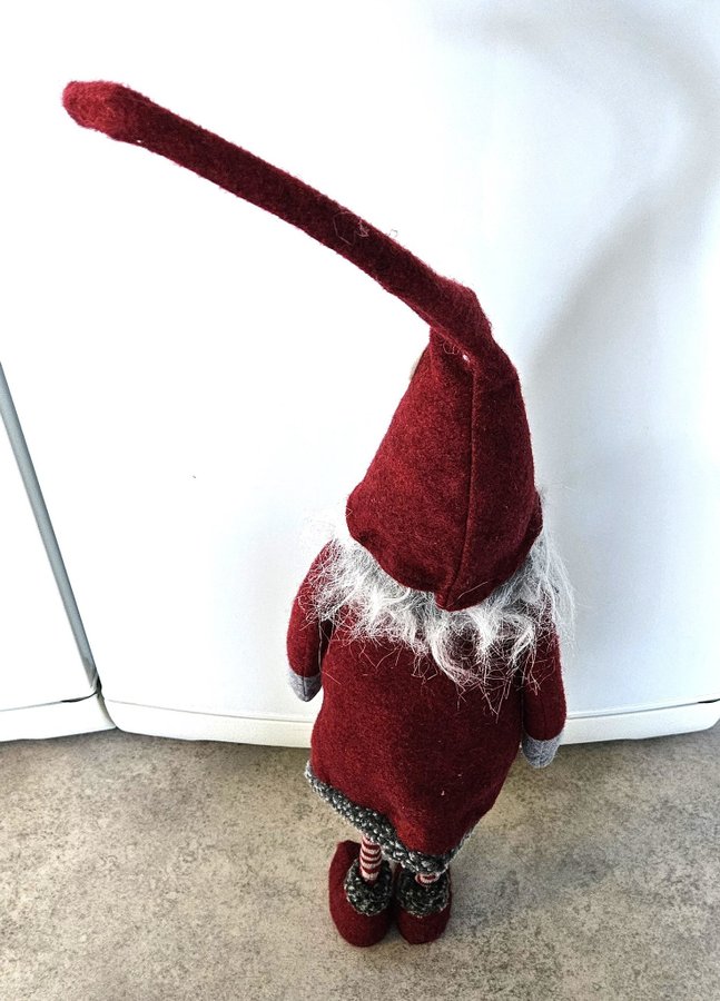 Stor söt tomte med långa smala ben och längt grått skägg.