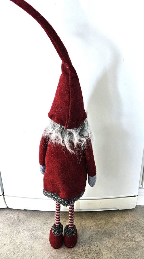 Stor söt tomte med långa smala ben och längt grått skägg.