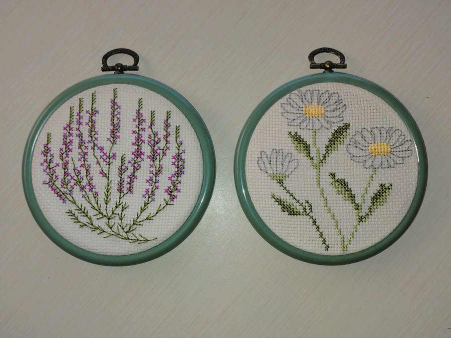 2 broderade runda tavlor med kamomill och lavender / grön ram i plast