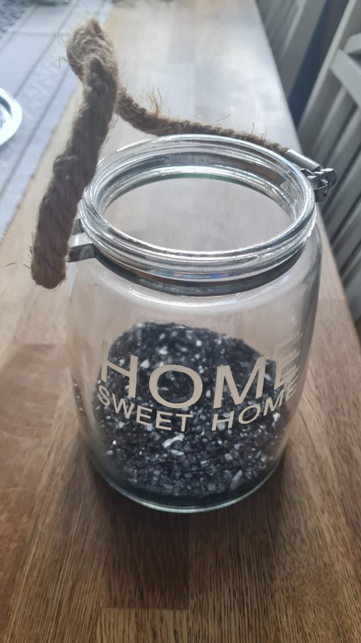 Ljuslykta med grovt snöre som handtag med texten "Home Sweet Home"