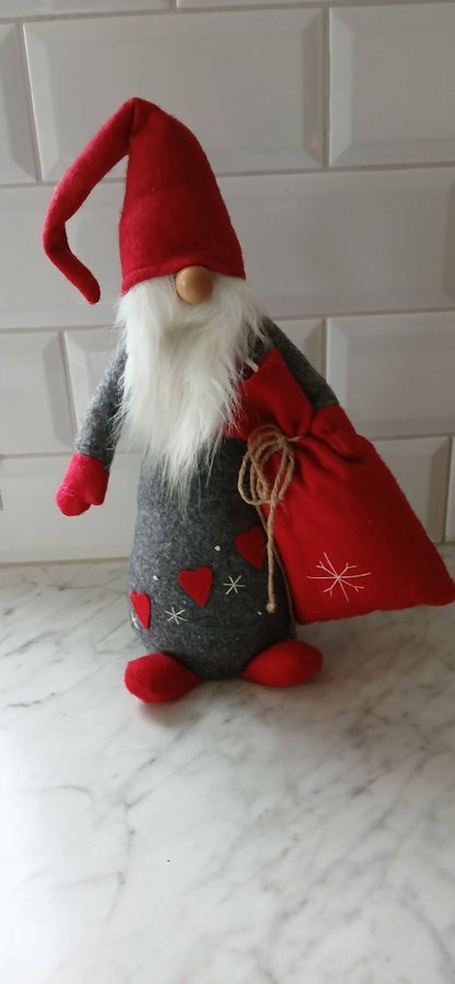 Jultomte i grått tyg med röd luva och säck