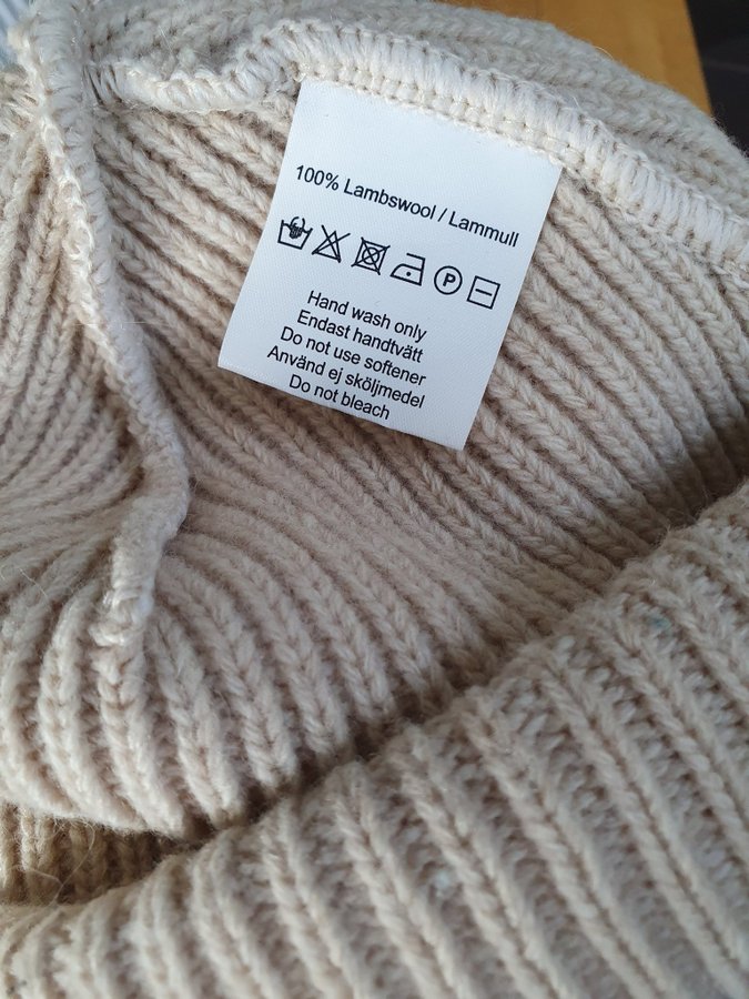 Beige mössa Canada Snow med en liten läderlapp på framsidan. Lammull.