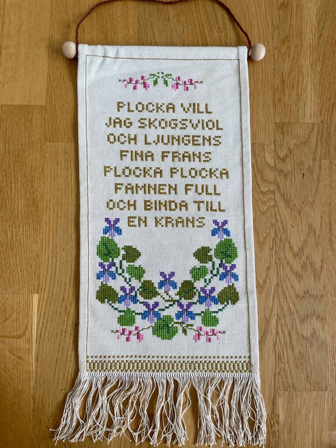 Handbroderad äldre väggbonad med blommor och text