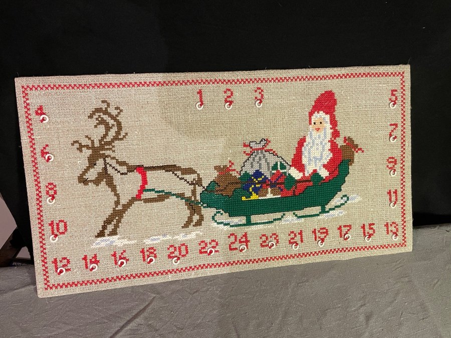 Broderad julkalender med korsstygn på tavla.