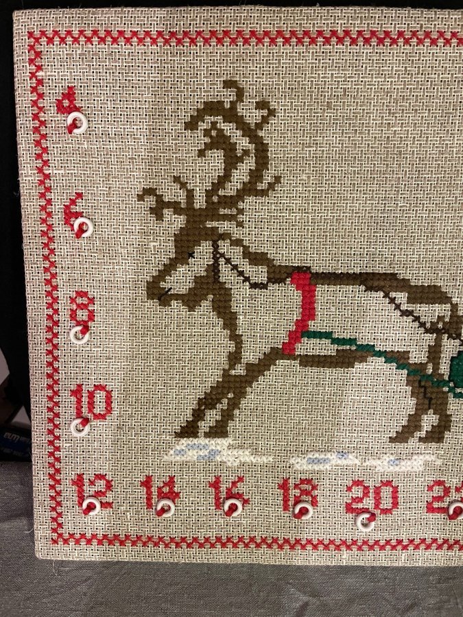 Broderad julkalender med korsstygn på tavla.